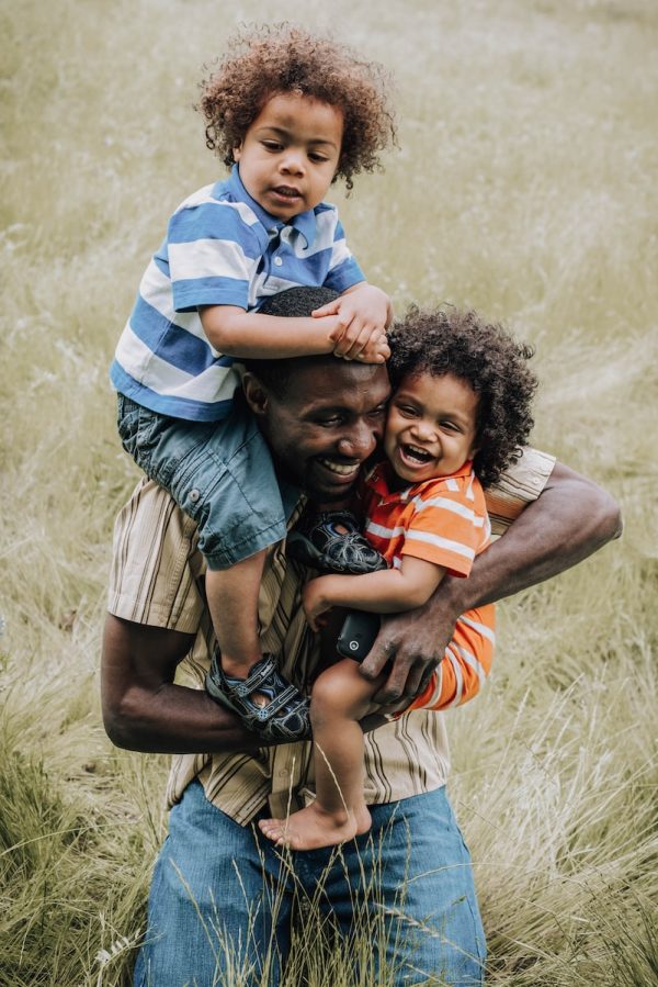 un homme noir tient dans ses bras ses enfants après un test de paternité
