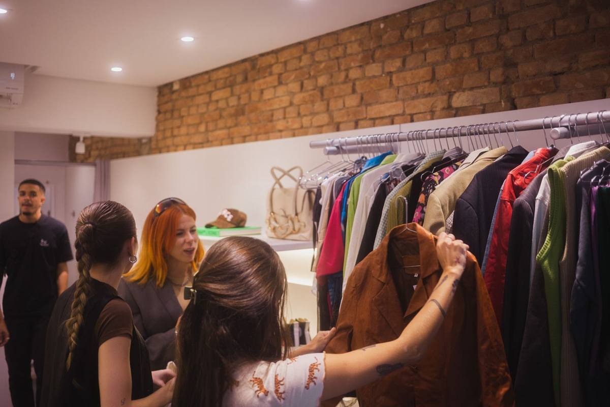 Femmes choisissent des vêtements dans une boutique, un homme observe Femmes choisissent des vêtements dans une boutique, un homme observe