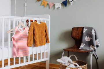 Berceau avec vêtements, panier de jouets, chaise avec couverture, bannières colorées